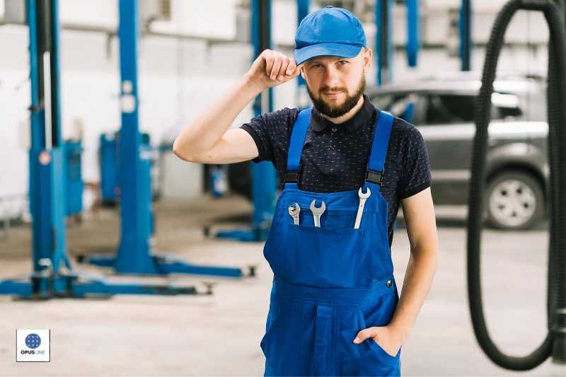 un mécanicien travaillant à l'intérieur de son atelier, vêtu d'une salopette bleue et d'une casquette - Quelles sont les conditions requises pour ouvrir un atelier d'usinage